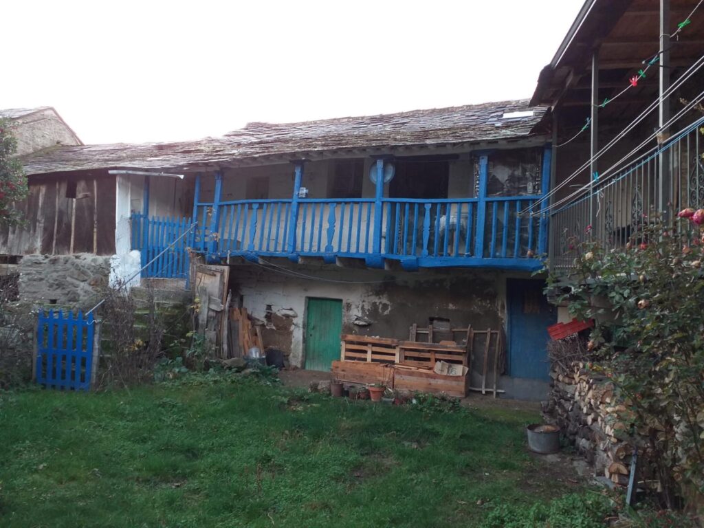 Casa con balcón azul de madera en Galende