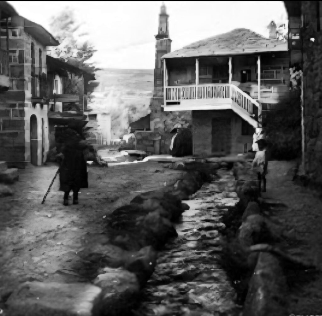 Fotografía antigua en blanco y negro de una calle de Galende con una vecina caminando